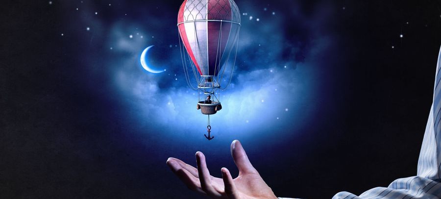 A creative depiction featuring a hot air balloon floating amid a celestial backdrop with a crescent moon and twinkling stars. A man's outstretched hand appears below, as if ready to catch or release it.