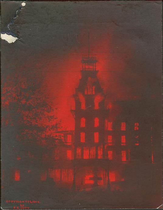 An early 20th-century photographic representation of a Victorian-style building bathed in a deep red glow, possibly conveying an unusual atmospheric event or celestial occurrence.