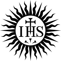 A monochrome emblem featuring the letters IHS in a stylized format with a cross above the 'H' and three nails below it, all enclosed within a circle.