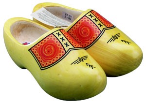 A pair of traditional Dutch wooden clogs painted in bright yellow with red and orange decorative patterns, including zigzag and cross motifs on the toe regions.