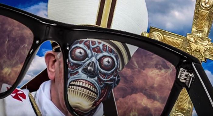 A surreal collage featuring an oversized pair of sunglasses framing symbolic elements including a menacing skull mask with starry eyes, and the visage of a figure dressed in a ceremonial outfit with a symbolic golden cross.