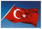 A vibrant red flag featuring a white crescent moon alongside a white star against a clear blue sky.