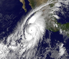 Satellite view of a large hurricane over the ocean near coastal land, demonstrating the mighty workings of creation, with thick swirling clouds centered around a distinct eye.