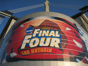A large, illuminated advertisement for the NCAA Final Four basketball tournament displayed on a curved building facade under a clear sky.