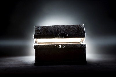 An illuminated antique book, glowing from within, placed on a dark surface under a beam of light, reminiscent of celestial navigation guides or old astronomical records.